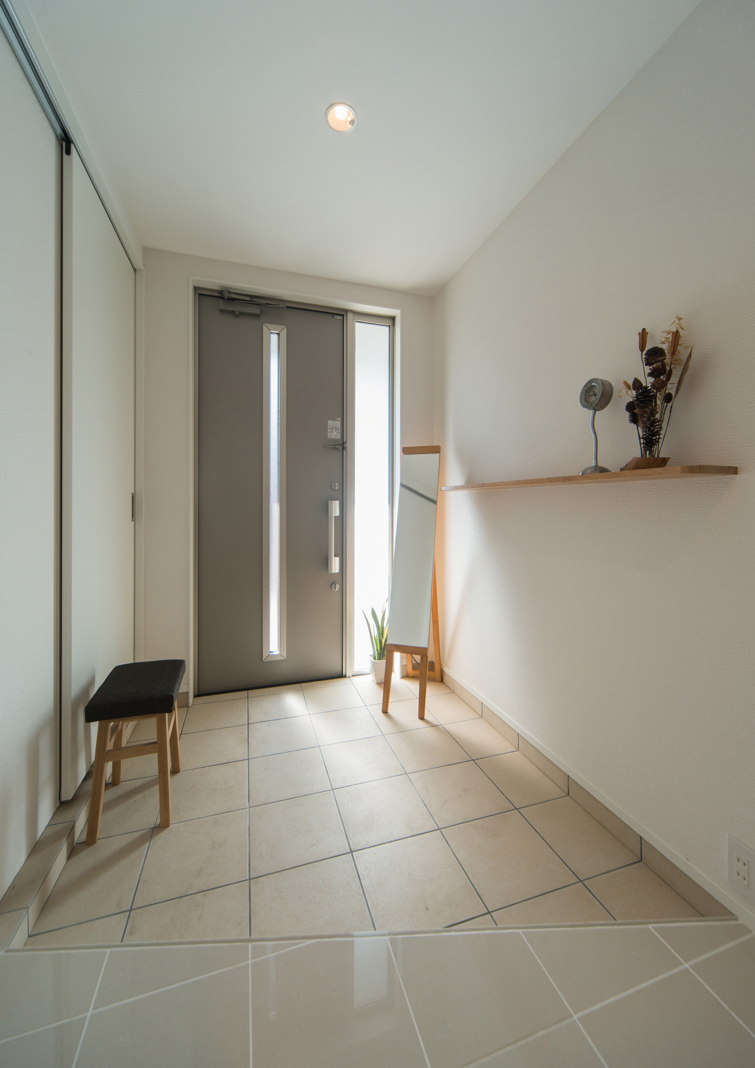 木の壁付け棚がある白いタイルの可愛らしい玄関・デザイン住宅 注文住宅・デザイン住宅建築実例_『CASE511 高台のガレージハウス』_玄関