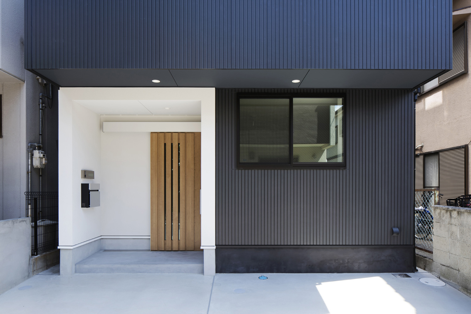 モノトーンの外壁で、木の玄関扉が取り付けられた外観の家・デザイン住宅 注文住宅・デザイン住宅建築実例_『CASE512 a　c　r　o　s　s』_外観