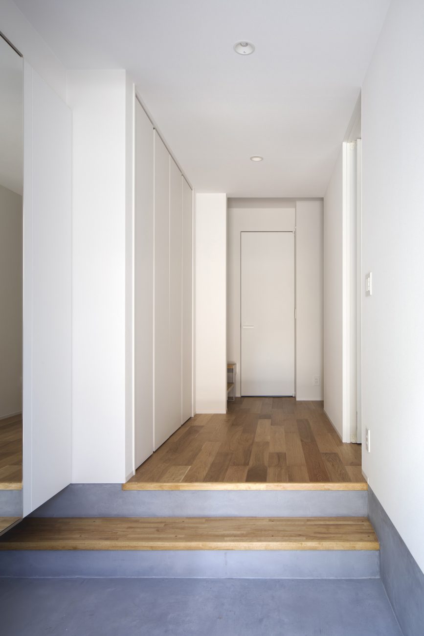 モルタルの玄関からフローリングで白い壁の廊下を見た様子・デザイン住宅 注文住宅・デザイン住宅建築実例_『CASE512 a　c　r　o　s　s』_玄関
