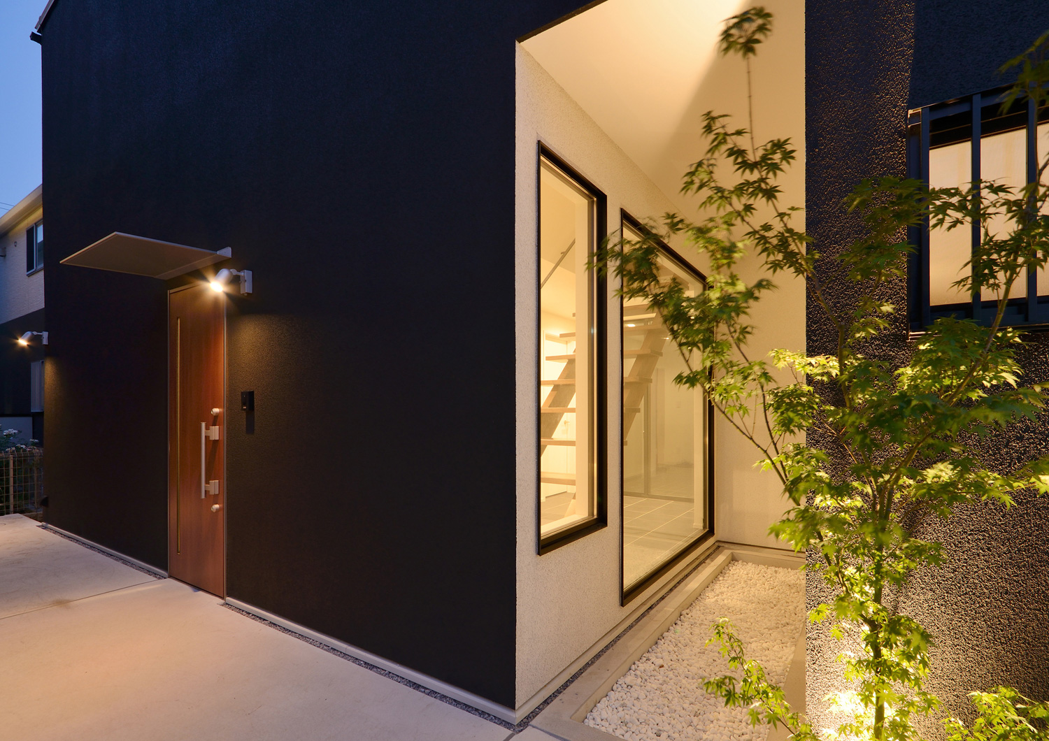 間接照明を取り付けた植栽があるモノトーンの外壁の玄関アプローチ・デザイン住宅 注文住宅・デザイン住宅建築実例_『CASE514 Slanting Hat』_外観