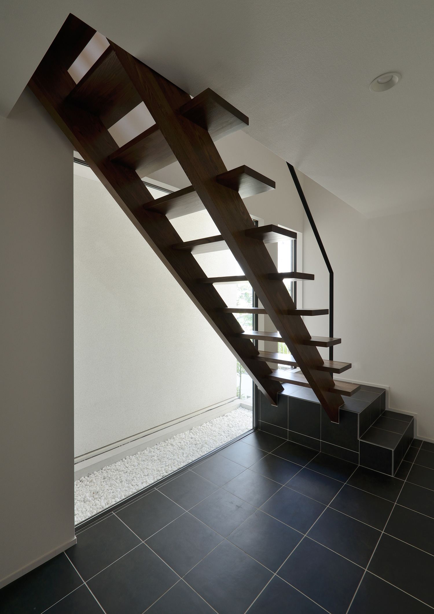 黒いタイルのフロアの窓際にある木製のスケルトン階段・デザイン住宅 注文住宅・デザイン住宅建築実例_『CASE514 Slanting Hat』_階段