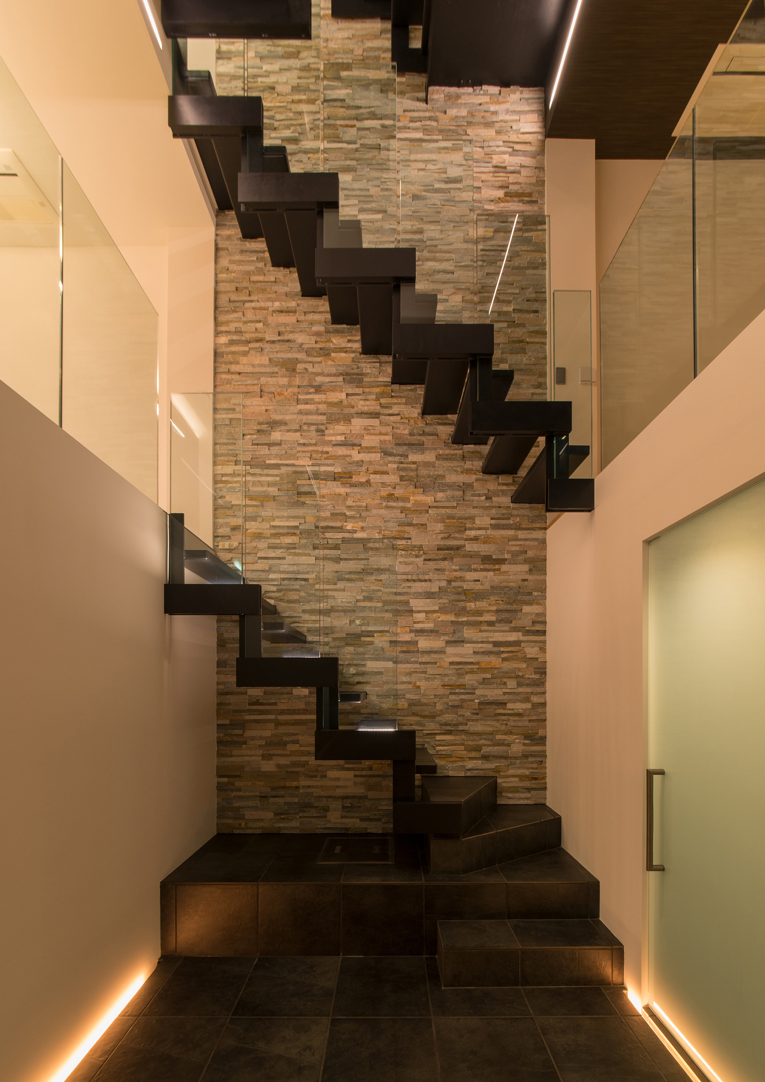 足元に間接照明を取り付けた吹き抜けでアクセントウォールのある階段室・デザイン住宅 注文住宅・デザイン住宅建築実例_『CASE518 The Residence』_玄関