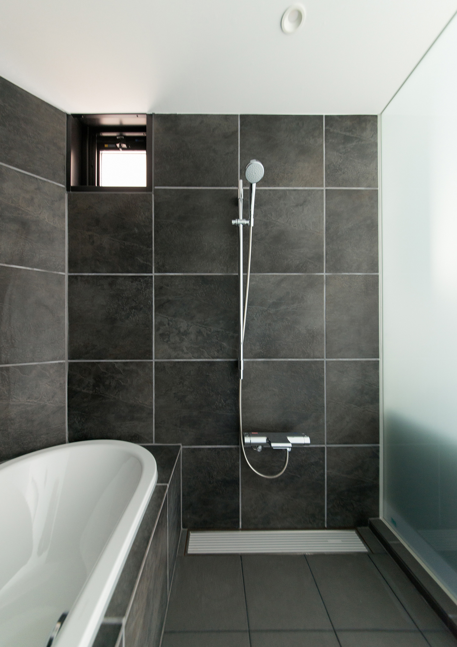 曇りガラスの壁がある、黒いタイルのホテルライクな浴室・デザイン住宅 注文住宅・デザイン住宅建築実例_『CASE518 The Residence』_浴室・洗面所