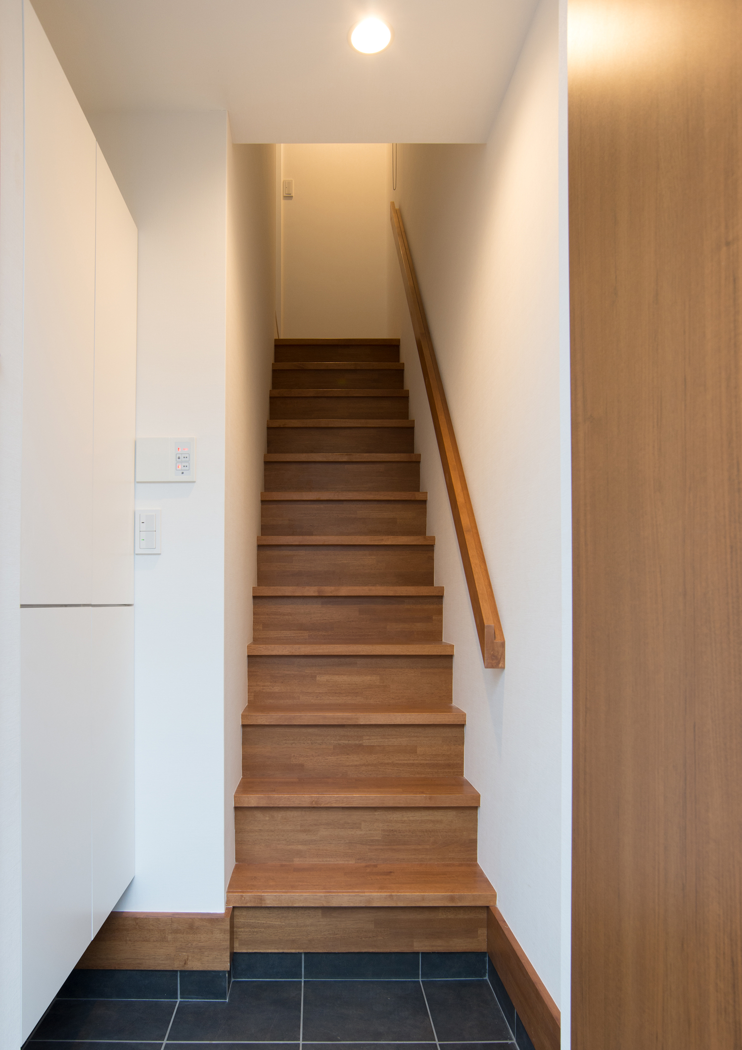 木の手すりが取り付けられたシンプルな箱型階段・デザイン住宅 注文住宅・デザイン住宅建築実例_『CASE523 くのじのいえ』_玄関