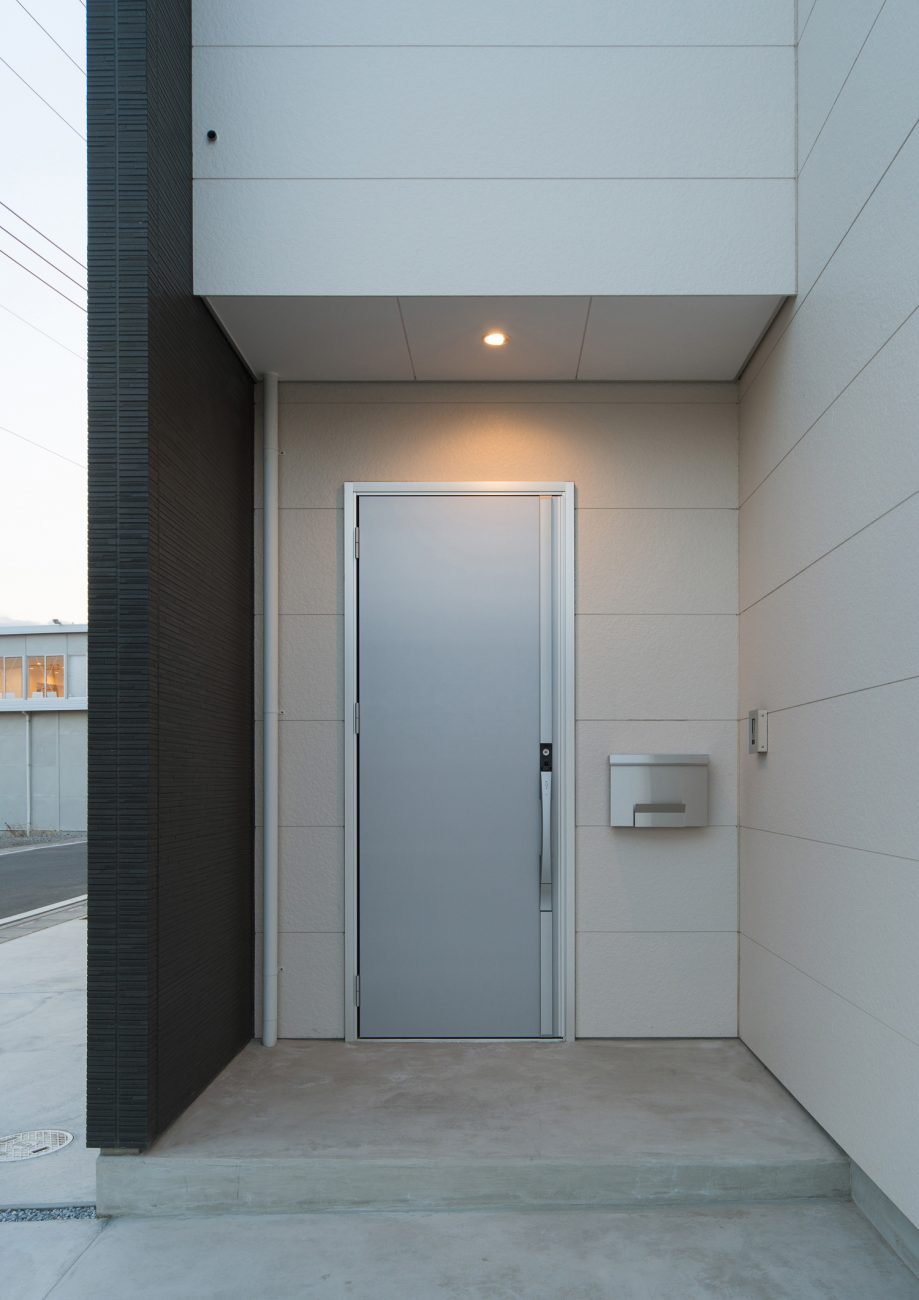 白い外壁にシルバーの玄関扉を取り付けたシンプルな玄関ポーチ・デザイン住宅 注文住宅・デザイン住宅建築実例_『CASE526 Two-tone』_外観
