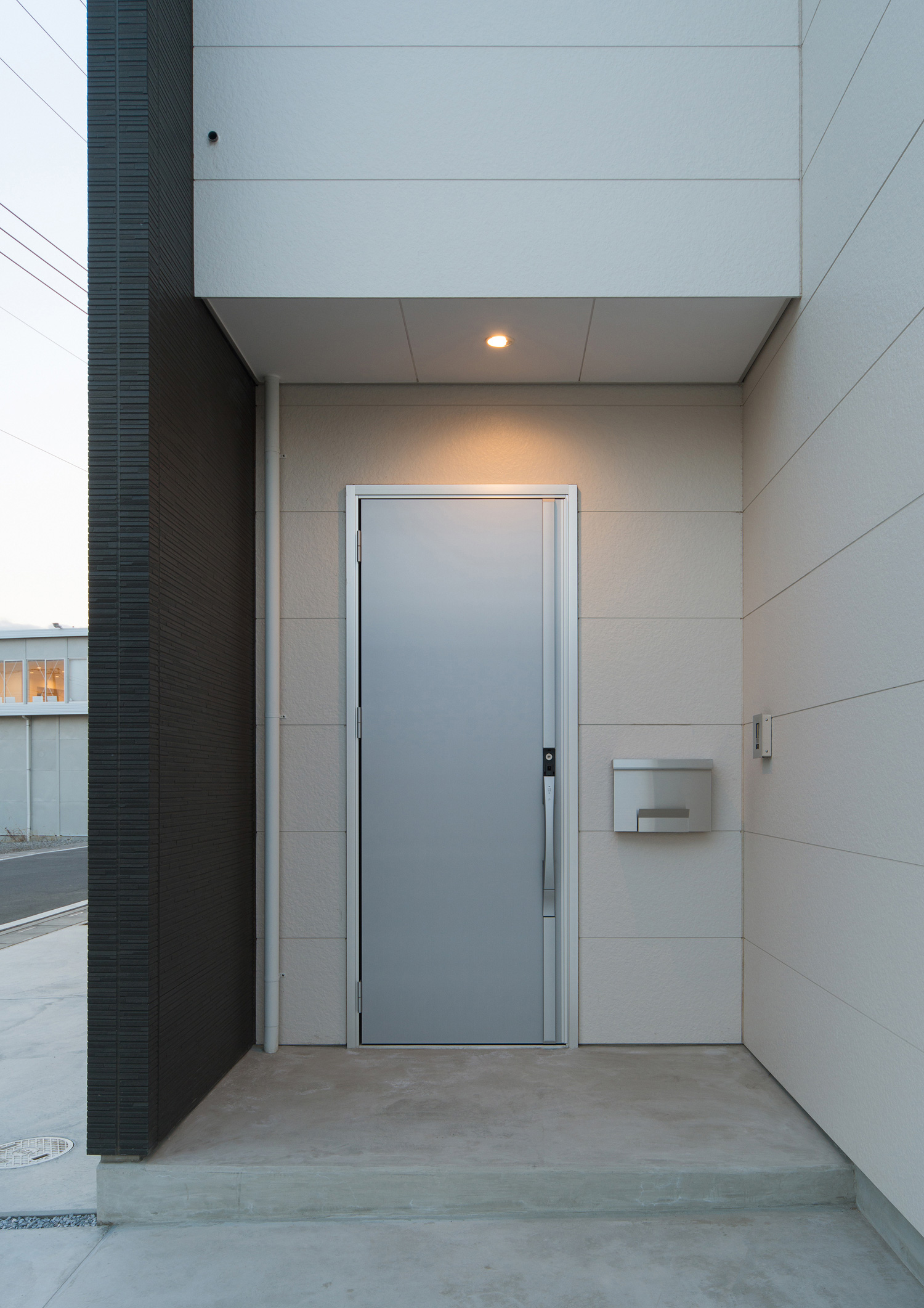 白い外壁にシルバーの玄関扉を取り付けたシンプルな玄関ポーチ・デザイン住宅 注文住宅・デザイン住宅建築実例_『CASE526 Two-tone』_外観