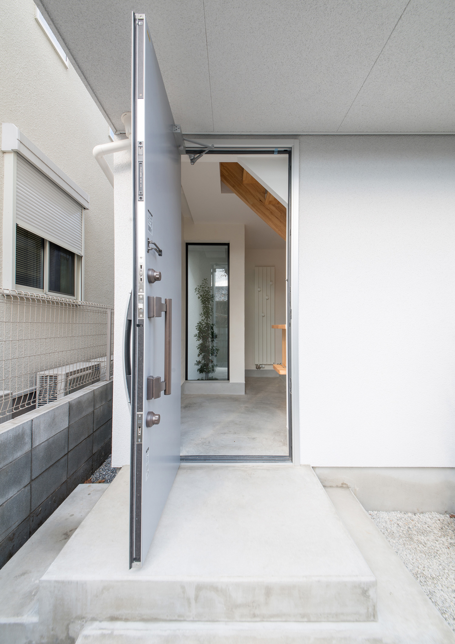 玄関扉を開けてモルタルの玄関が見える様子・デザイン住宅 注文住宅・デザイン住宅建築実例_『CASE541 寄棟天井のある家』_外観