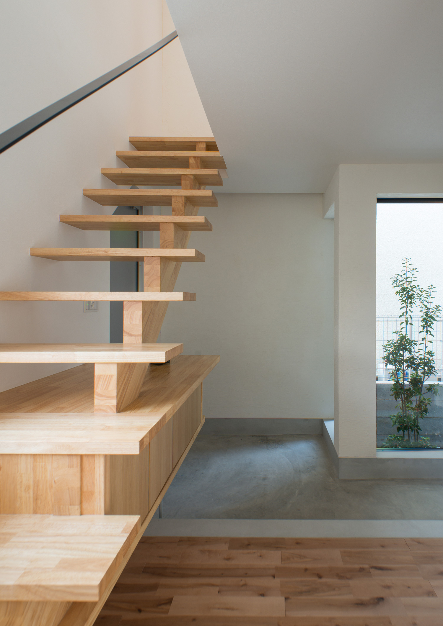 モルタルの土間玄関を横切る木製のスケルトン階段・デザイン住宅 注文住宅・デザイン住宅建築実例_『CASE541 寄棟天井のある家』_玄関