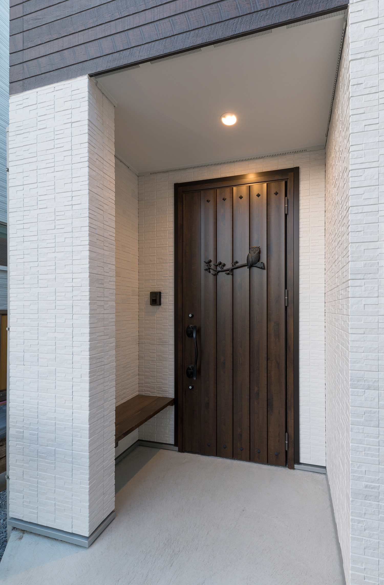 白い外壁に濃いブラウンの玄関扉が取り付けられた玄関ポーチ・デザイン住宅 注文住宅・デザイン住宅建築実例_『CASE546 ウォールナットとガラスの家』_外観