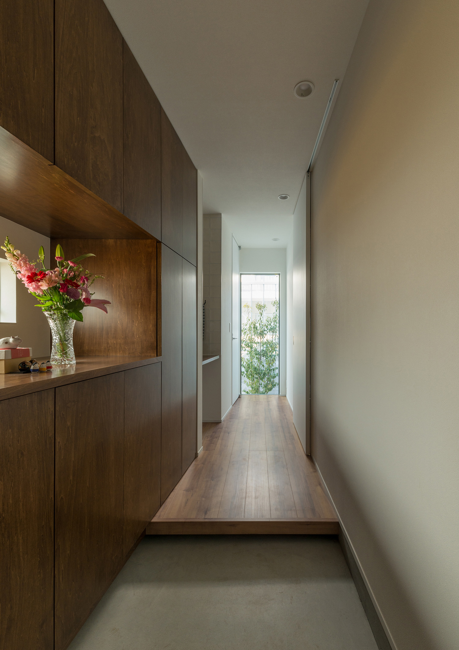 正面にシンボルツリーがある窓を設けた木のシューズボックスを取り付けた玄関・デザイン住宅 注文住宅・デザイン住宅建築実例_『CASE546 ウォールナットとガラスの家』_玄関