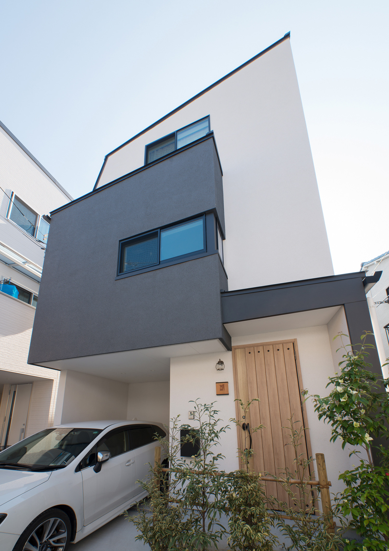 木製の玄関扉を取り付けたモノトーンの外観の三階建て住宅・デザイン住宅 注文住宅・デザイン住宅建築実例_『CASE547 移ろいの家』_外観