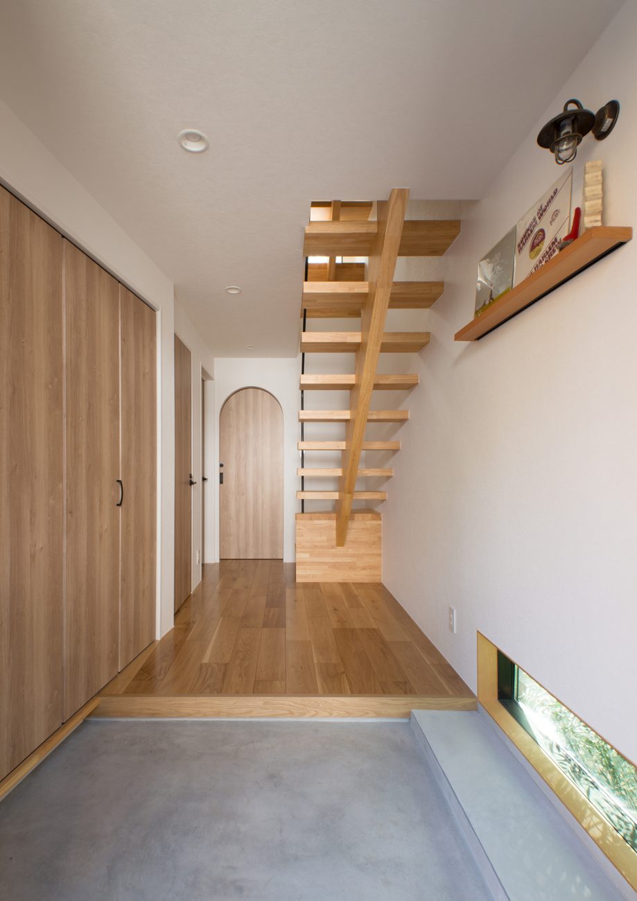 地窓付きのモルタルの玄関の正面に木製のスケルトン階段がある様子・デザイン住宅 注文住宅・デザイン住宅建築実例_『CASE547 移ろいの家』_玄関