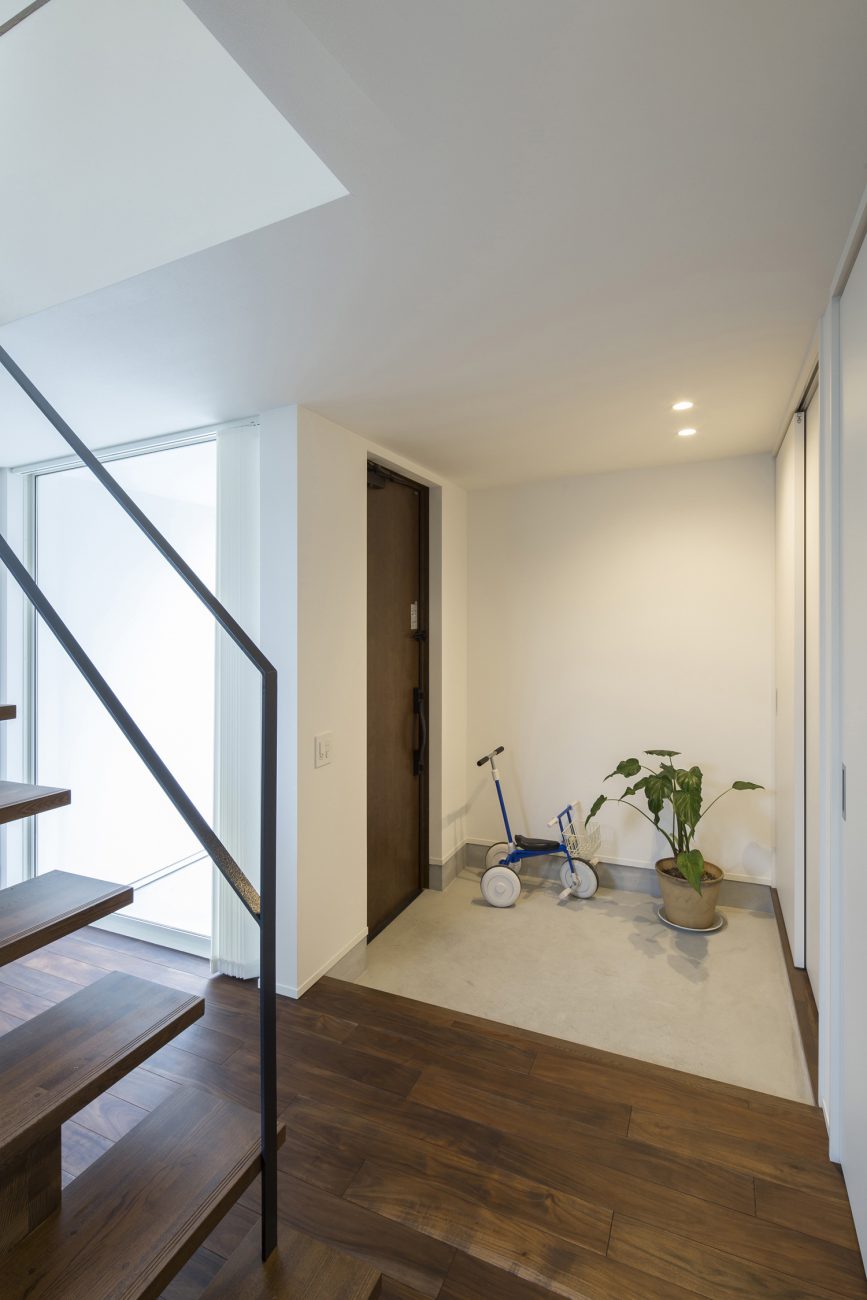 観葉植物や三輪車を置くスペースがあるモルタルの玄関・デザイン住宅 注文住宅・デザイン住宅建築実例_『CASE557 いろどり』_玄関