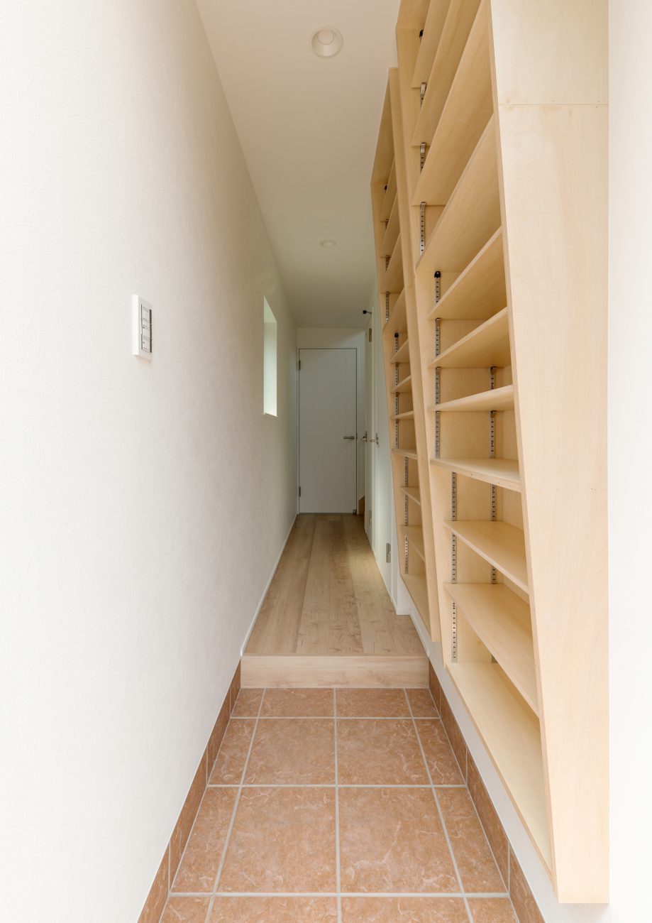 天井までの高さがある木製のシューズボックスを壁に取り付けた玄関・デザイン住宅 注文住宅・デザイン住宅建築実例_『CASE562 タテ長い家』_玄関