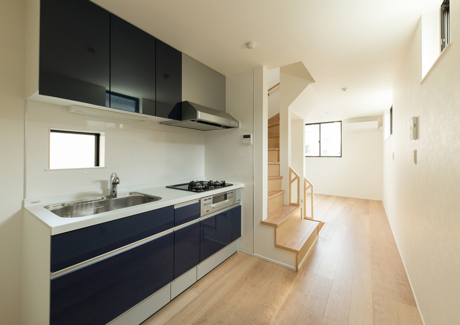 階段の隣にある青い壁付けキッチン・デザイン住宅 注文住宅・デザイン住宅建築実例_『CASE562 タテ長い家』_LDK