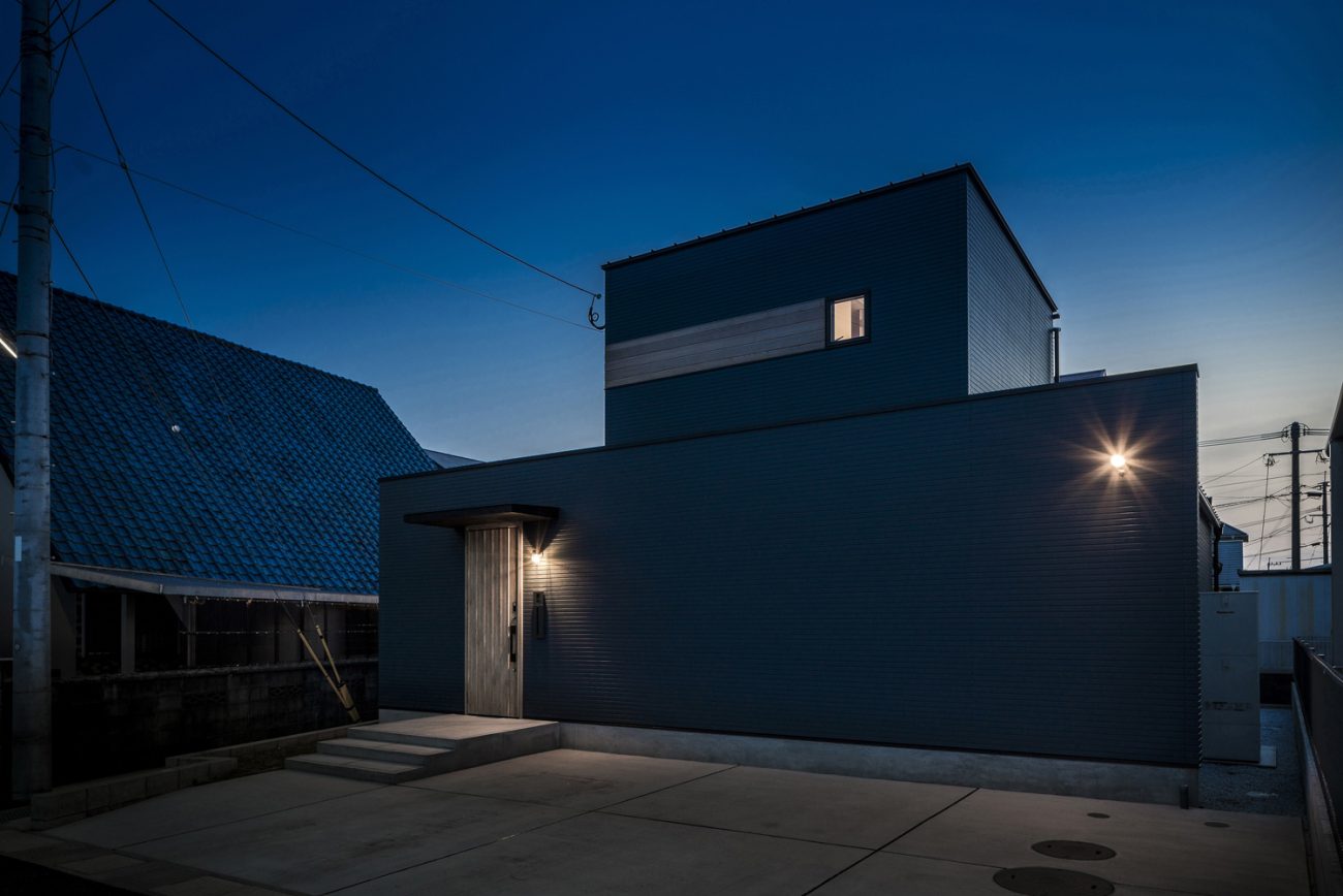 ネイビーの外壁に照明が取り付けられた家を斜めから見た様子・デザイン住宅 注文住宅・デザイン住宅建築実例_『CASE563 pocket』_外観