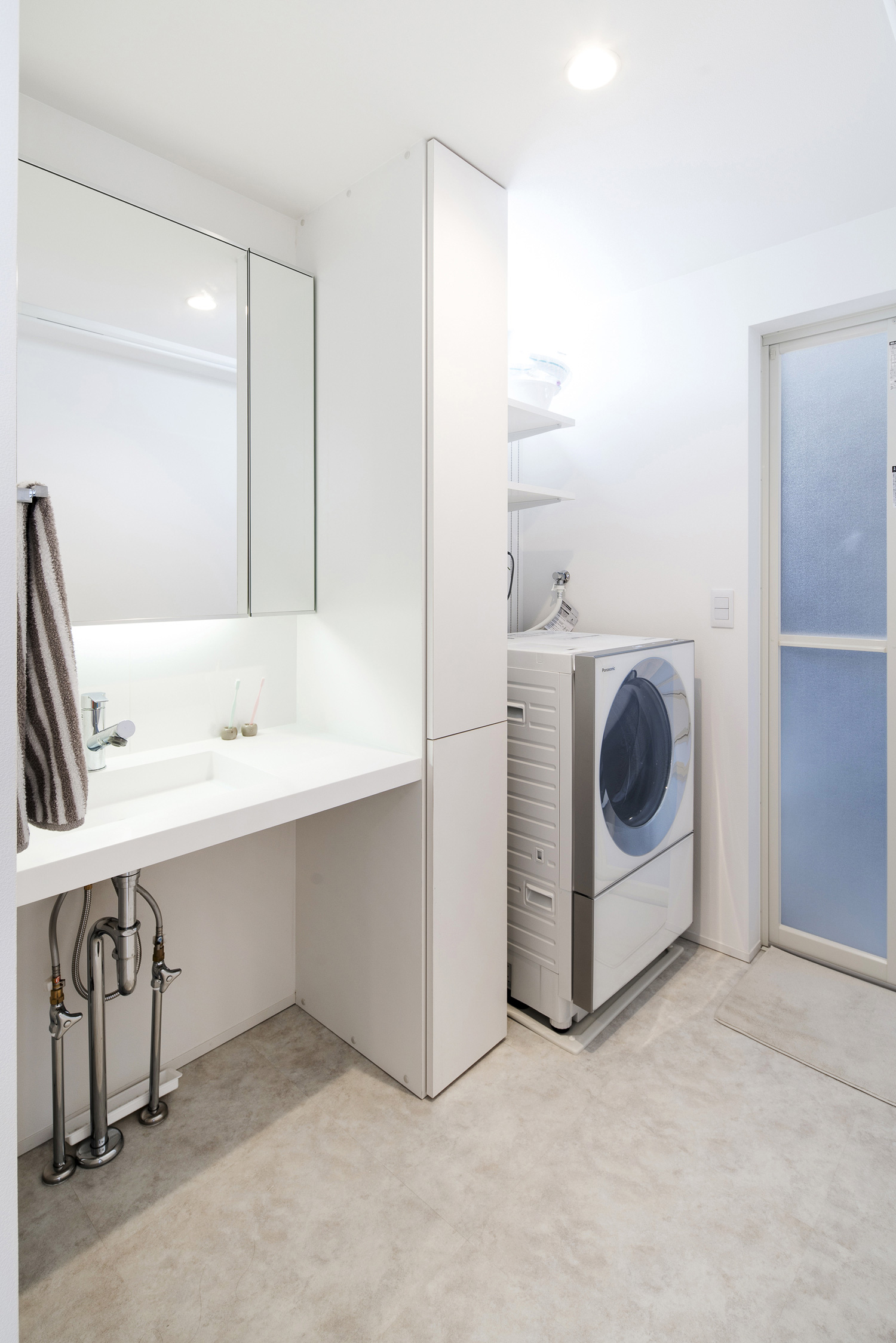 洗面台と洗濯機の間に収納棚がある白を基調とした明るい洗面所・デザイン住宅 注文住宅・デザイン住宅建築実例_『CASE563 pocket』_浴室・洗面所