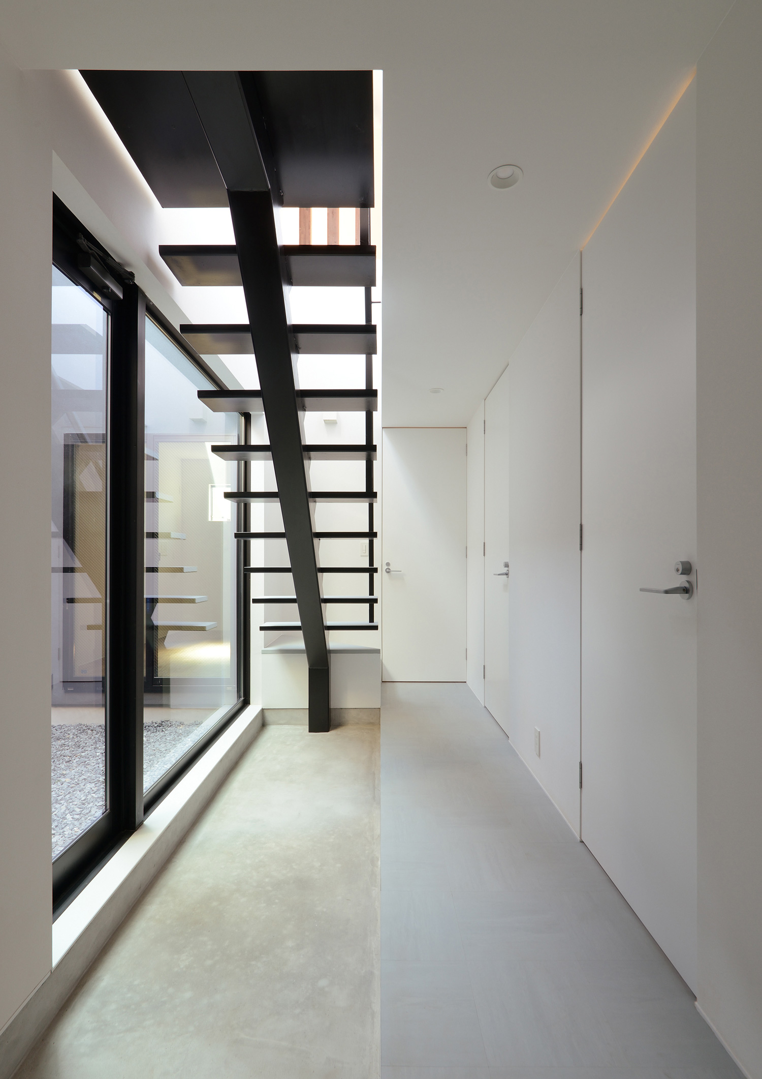 スケルトン階段下のスペースにあるモルタルの土間玄関・デザイン住宅 注文住宅・デザイン住宅建築実例_『CASE566 拡がりを内包する黒庭』_玄関