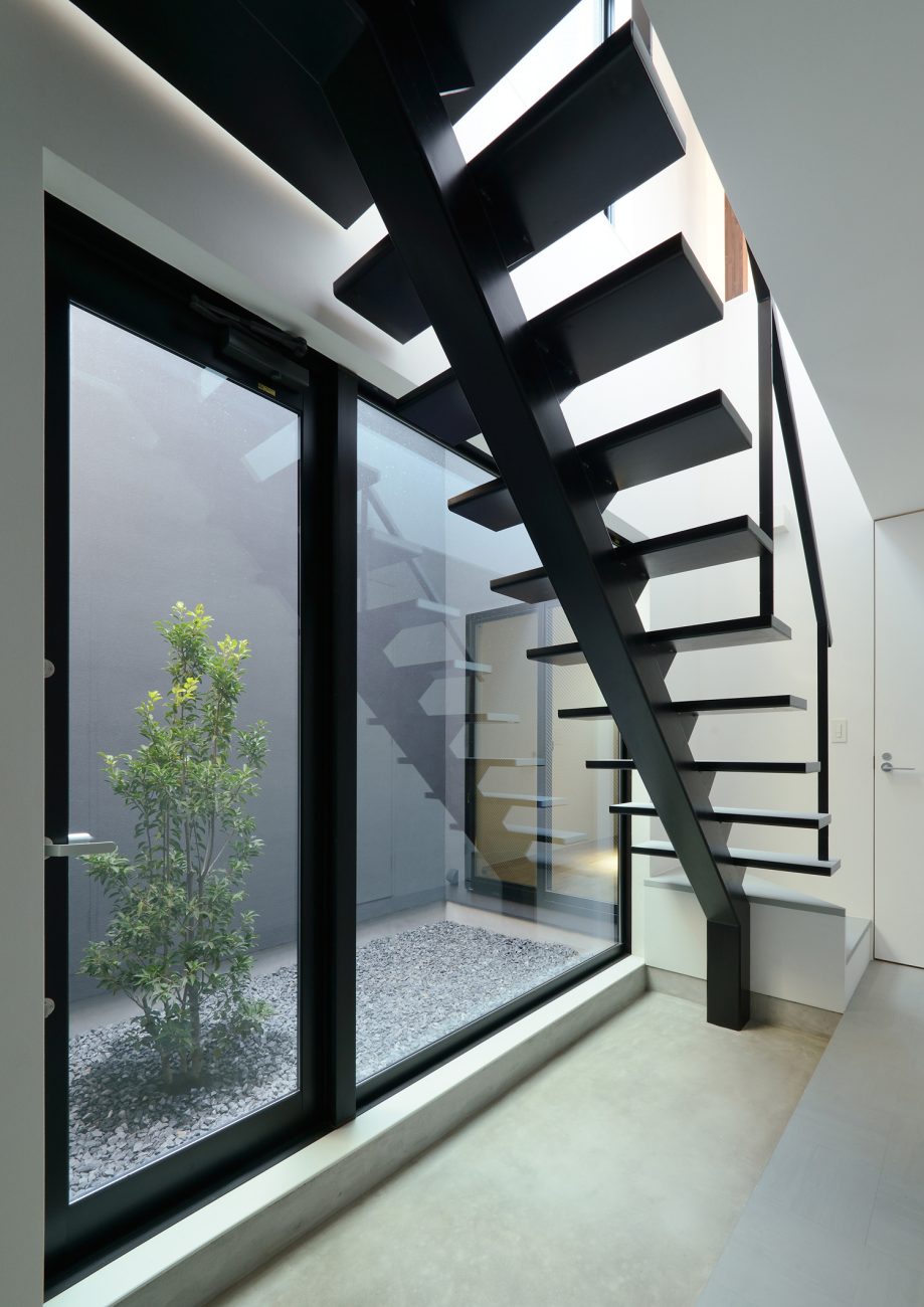 中庭に面した窓があるシンプルでおしゃれなモルタルの土間玄関・デザイン住宅 注文住宅・デザイン住宅建築実例_『CASE566 拡がりを内包する黒庭』_玄関