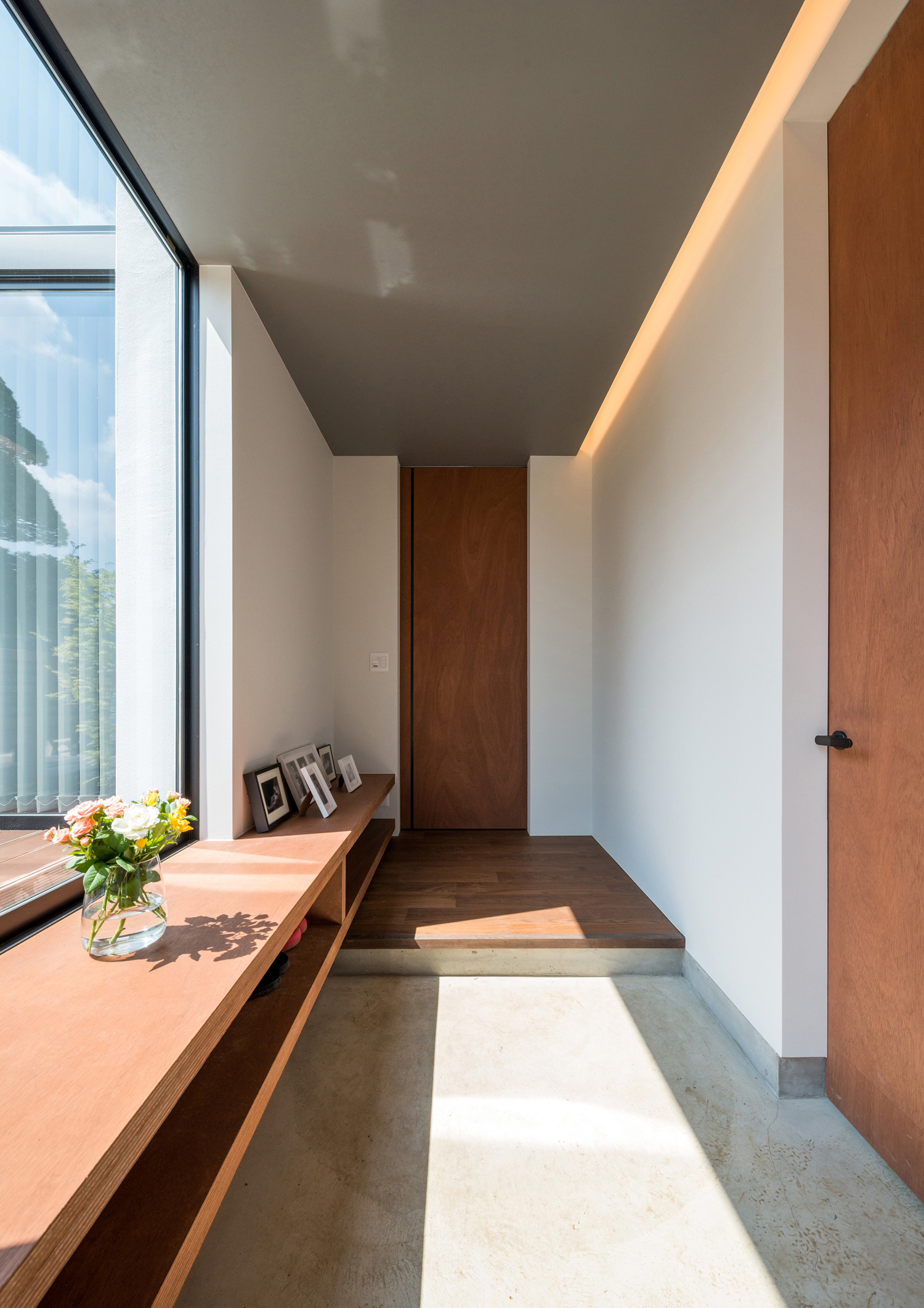 テラスに面した大きな窓がある明るいモルタルの玄関・デザイン住宅 注文住宅・デザイン住宅建築実例_『CASE573 次代の家』_玄関