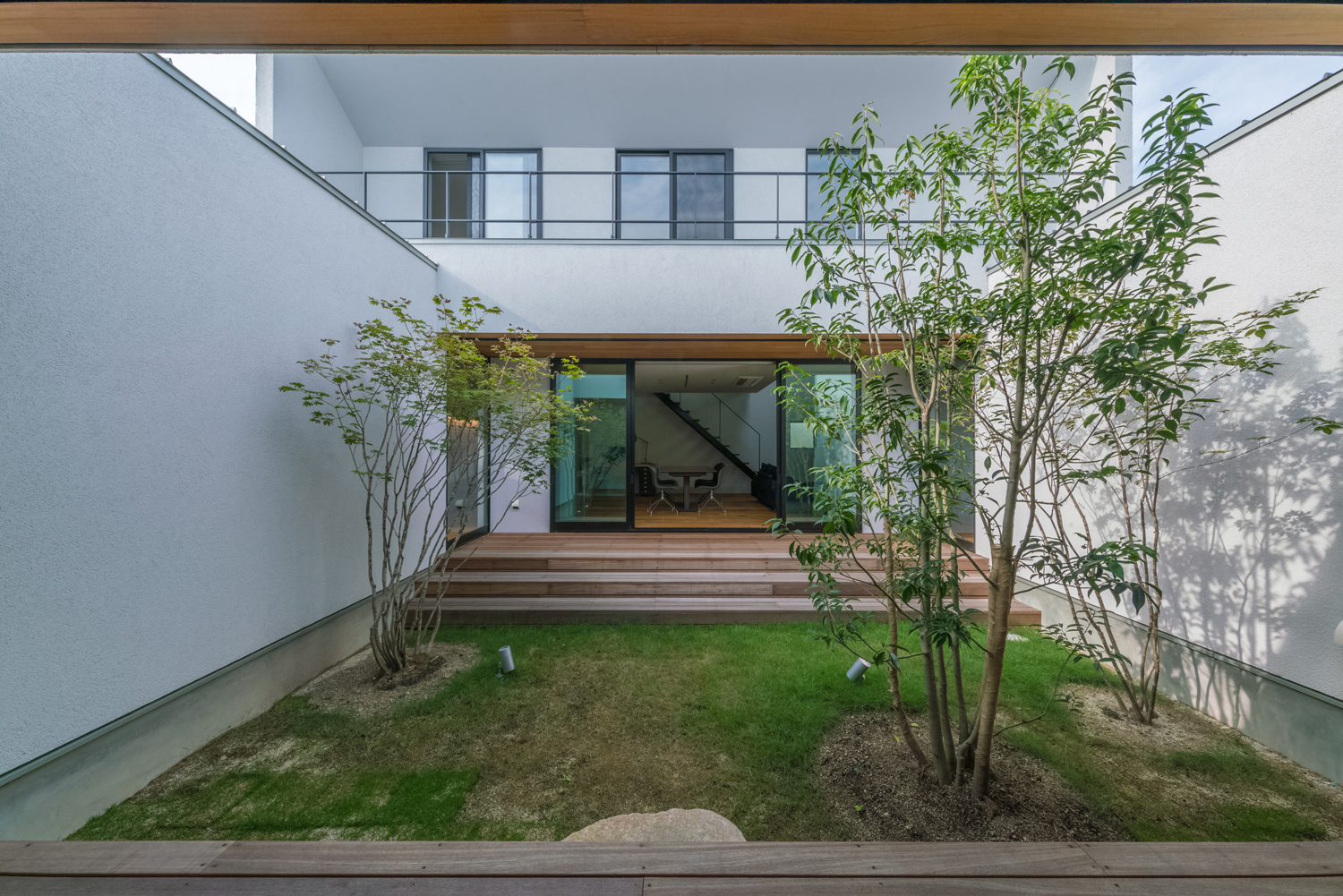 白い壁に囲まれた、芝生や植栽のある中庭・デザイン住宅 注文住宅・デザイン住宅建築実例_『CASE576 回廊の家』_中庭