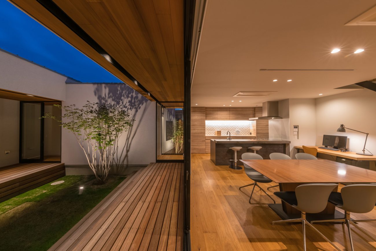 植栽がライトアップされたウッドデッキ付きの中庭とフラットに繋がるLDK・デザイン住宅 注文住宅・デザイン住宅建築実例_『CASE576 回廊の家』_中庭