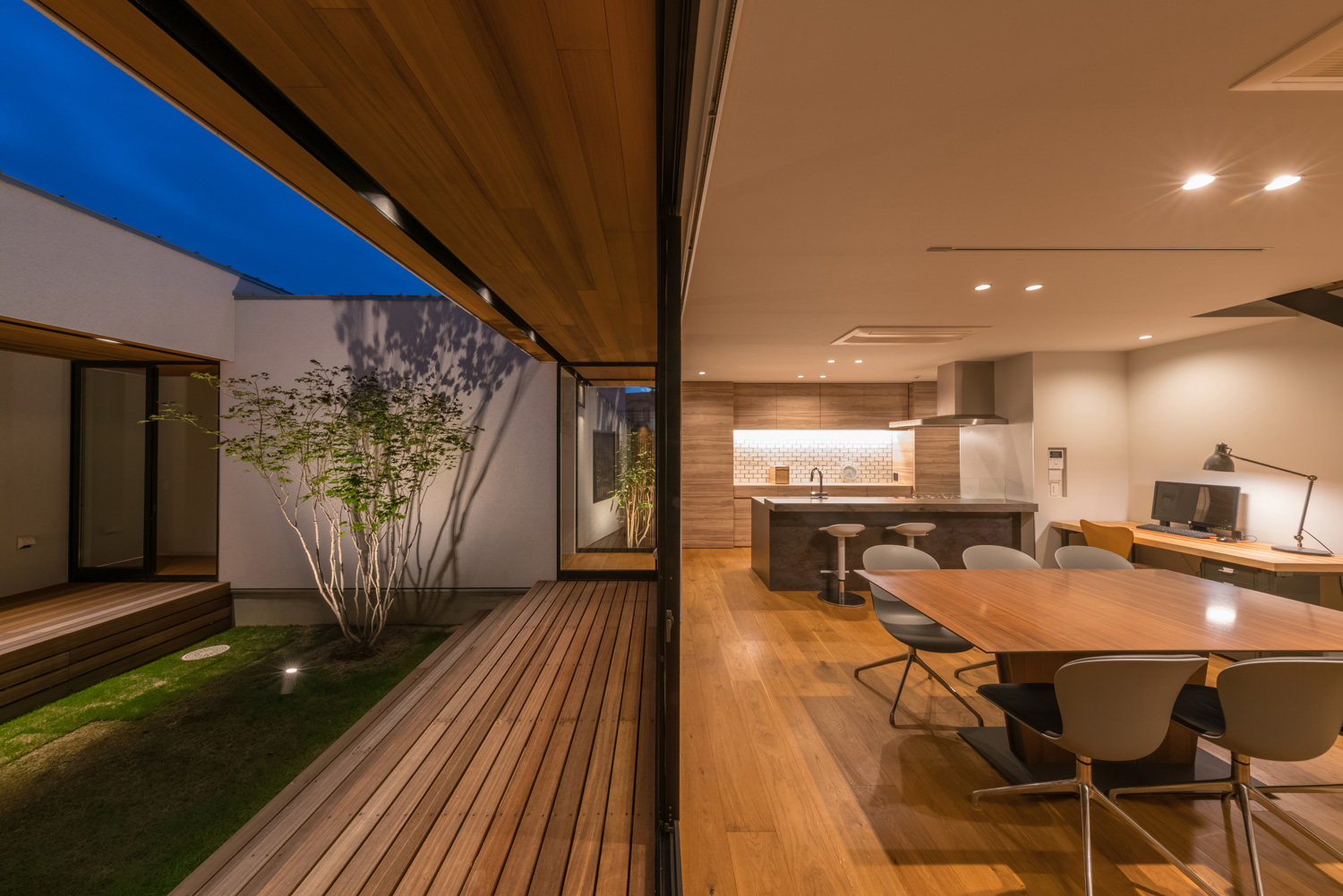 植栽がライトアップされたウッドデッキ付きの中庭とフラットに繋がるLDK・デザイン住宅 注文住宅・デザイン住宅建築実例_『CASE576 回廊の家』_中庭