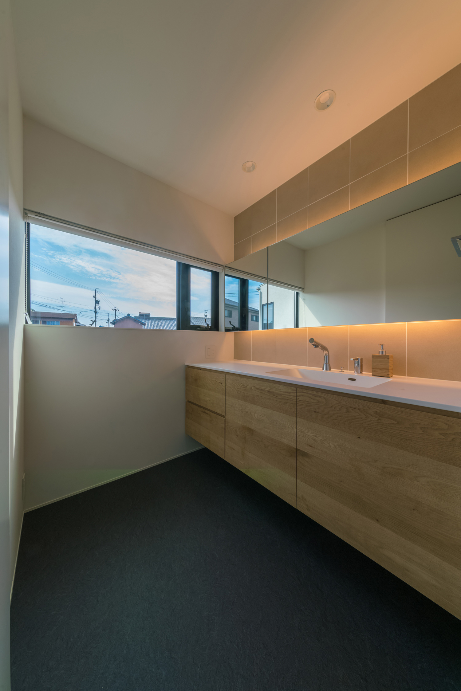 タイルの壁に間接照明付きの鏡を取り付けた洗面所・デザイン住宅 注文住宅・デザイン住宅建築実例_『CASE576 回廊の家』_浴室・洗面所