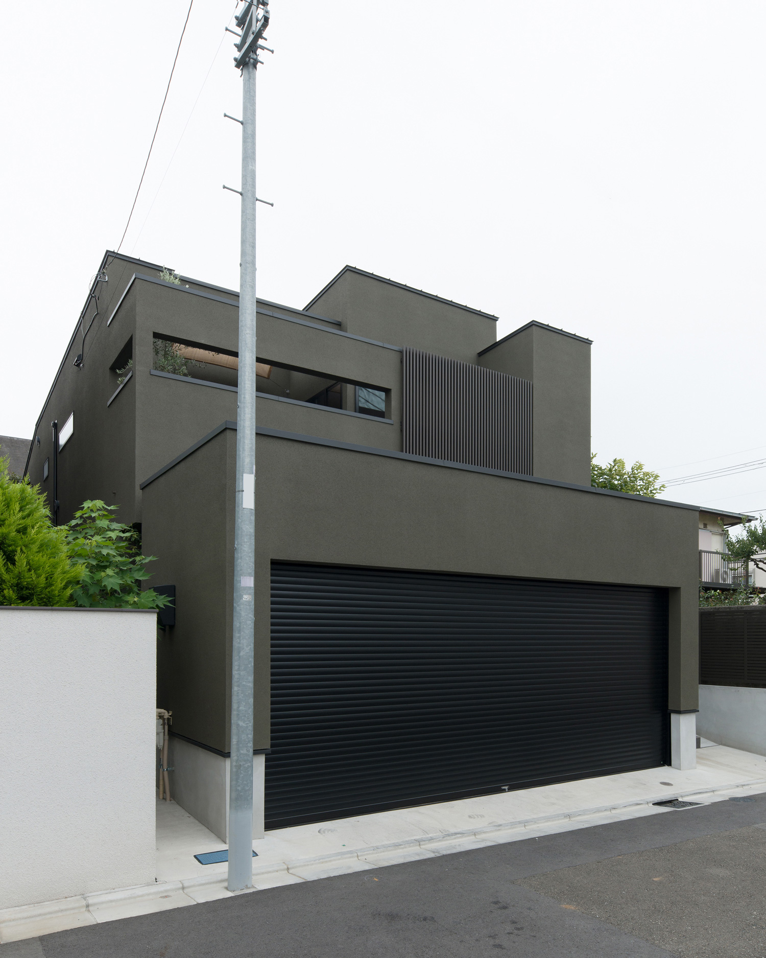 黒いシャッター付きのガレージや目隠し壁付きのベランダがあるカーキの外壁の家・デザイン住宅 注文住宅・デザイン住宅建築実例_『CASE577 紬（つむぎ）の家』_外観