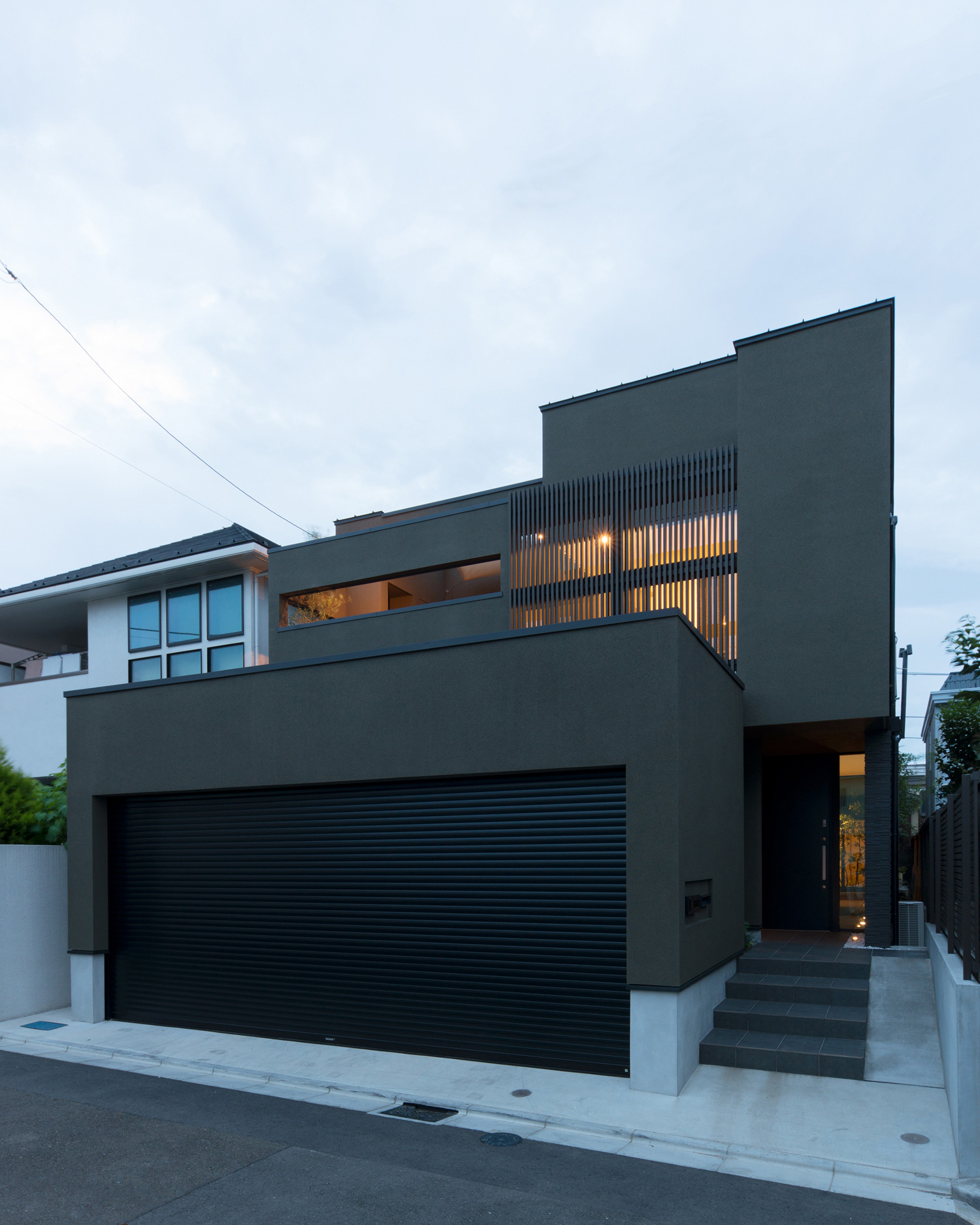 ベランダにあるルーバーの目隠しや玄関扉の横の窓から光が漏れる外観・デザイン住宅 注文住宅・デザイン住宅建築実例_『CASE577 紬（つむぎ）の家』_外観