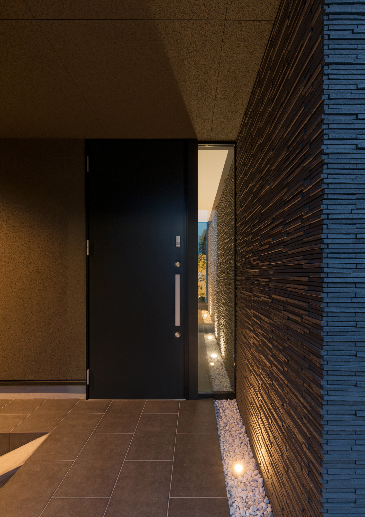 黒い玄関扉の横に縦長のスリット窓があるタイルの玄関・デザイン住宅 注文住宅・デザイン住宅建築実例_『CASE577 紬（つむぎ）の家』_外観