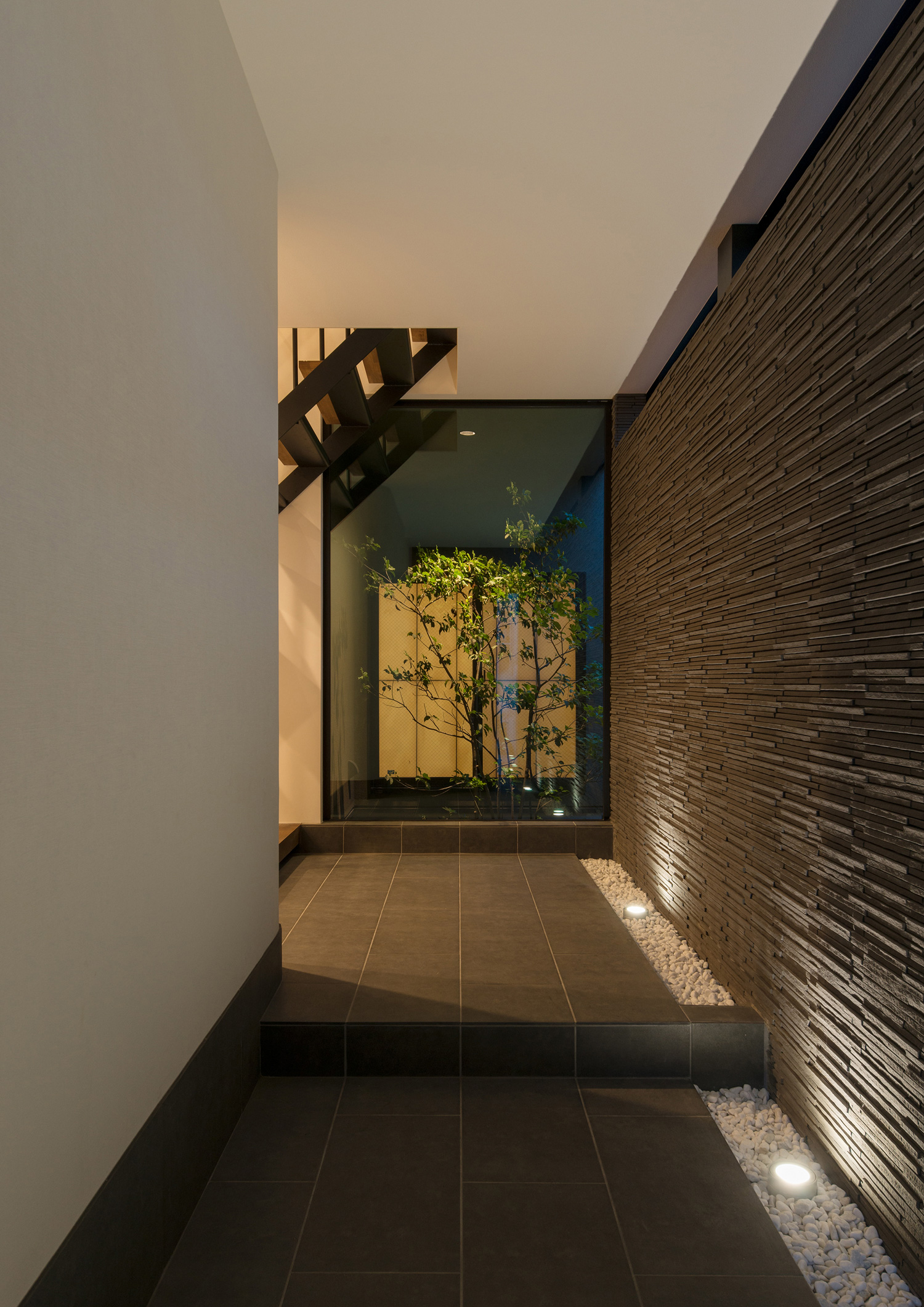 壁際の敷石に照明を取り付けて壁を照らした玄関・デザイン住宅 注文住宅・デザイン住宅建築実例_『CASE577 紬（つむぎ）の家』_玄関