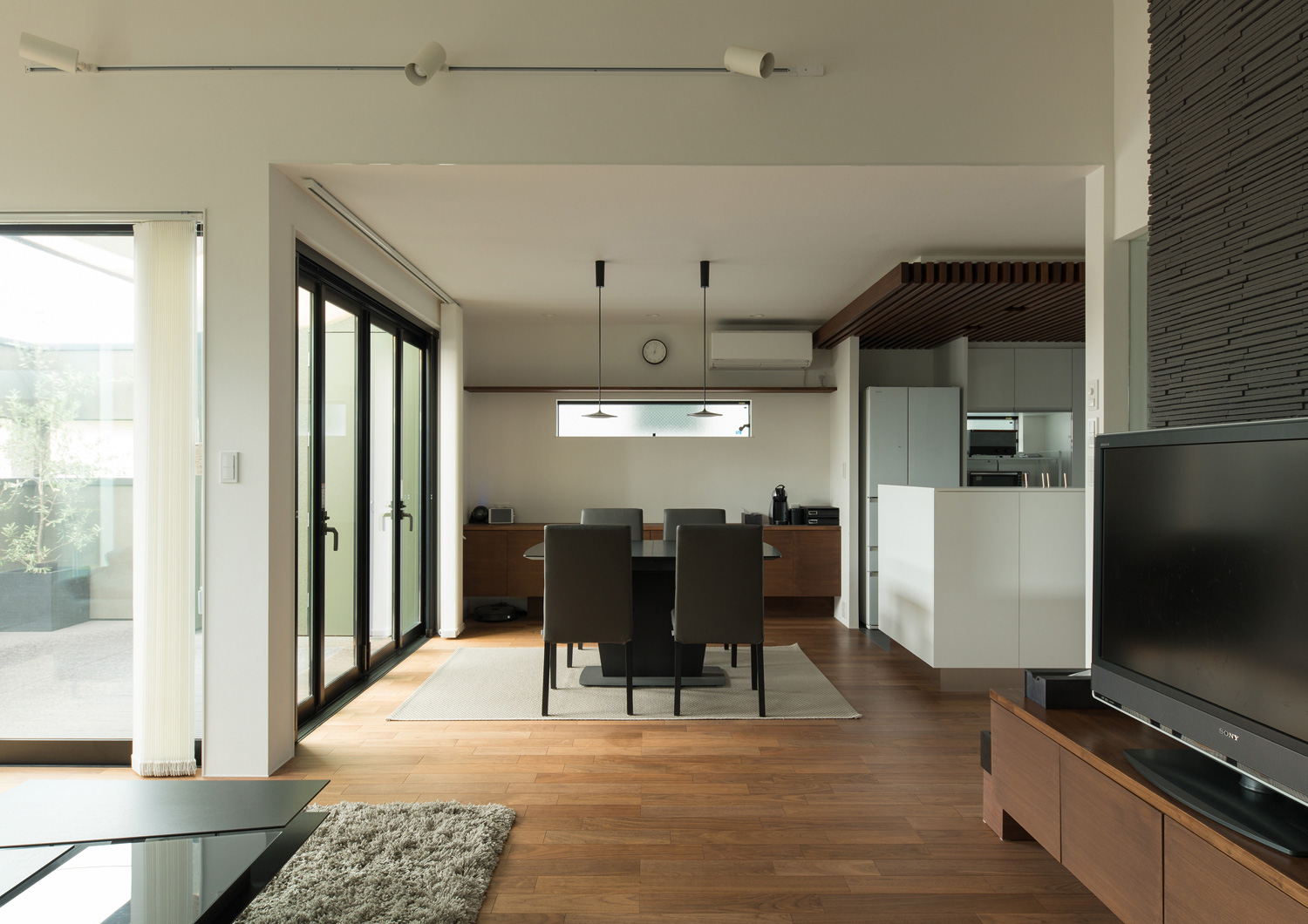 黒いダイニングテーブル部分にカーペットが敷かれたフローリングのLDK・デザイン住宅 注文住宅・デザイン住宅建築実例_『CASE577 紬（つむぎ）の家』_LDK