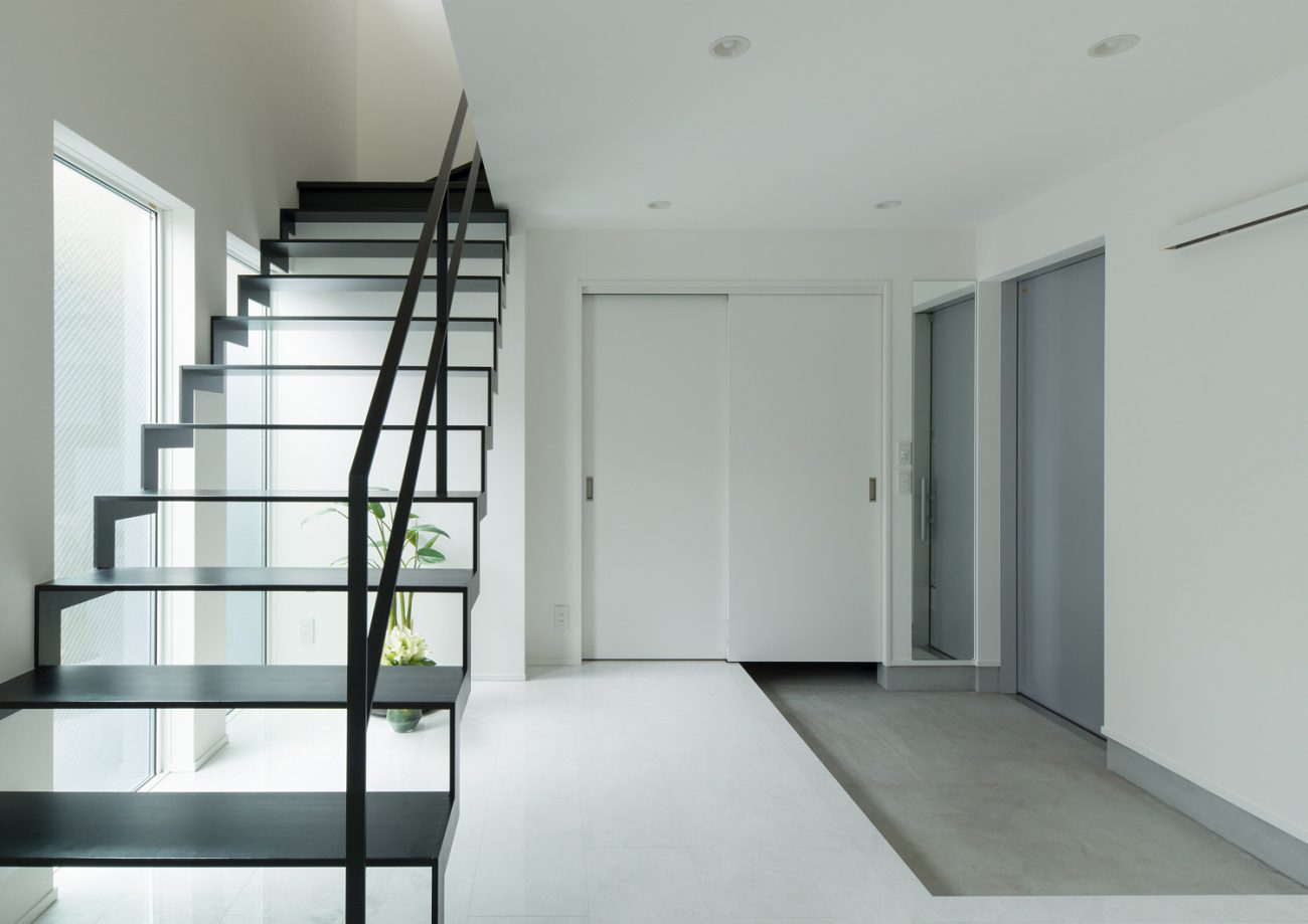 モルタルの玄関の正面にある、黒いアイアンのスケルトン階段・デザイン住宅 注文住宅・デザイン住宅建築実例_『CASE579 Functional House』_玄関