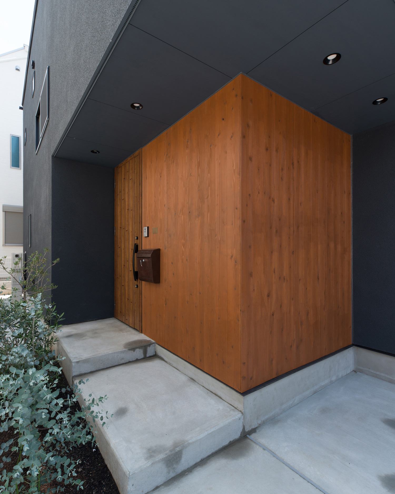 木目の壁と木の玄関扉がある玄関アプローチ・デザイン住宅 注文住宅・デザイン住宅建築実例_『CASE582 大切な時を刻む家』_外観