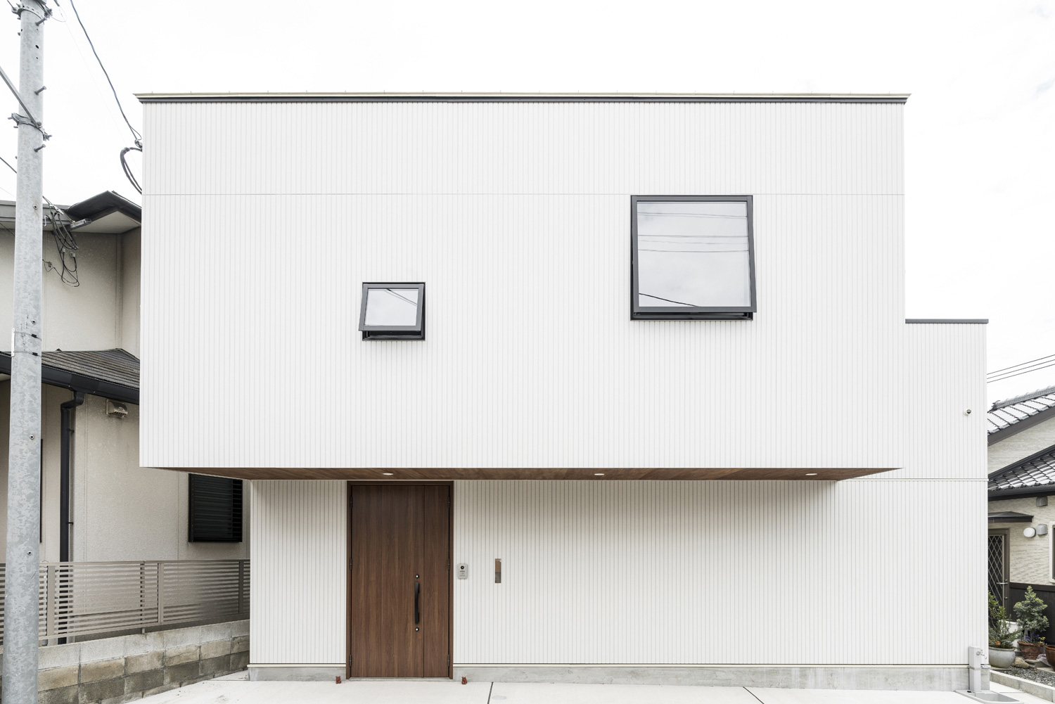正方形の窓と木目の扉が取り付けられた白い外壁のスクエアな家・デザイン住宅 注文住宅・デザイン住宅建築実例_『CASE583 デルタ』_外観