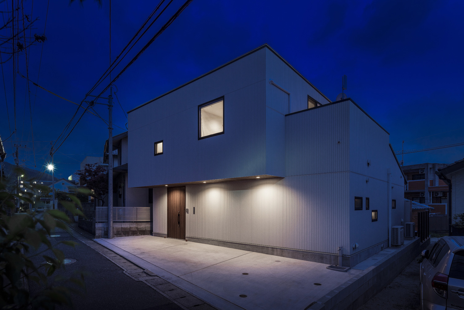 軒天井にダウンライトが取り付けられた木目の玄関扉付きの白い外壁の家・デザイン住宅 注文住宅・デザイン住宅建築実例_『CASE583 デルタ』_外観