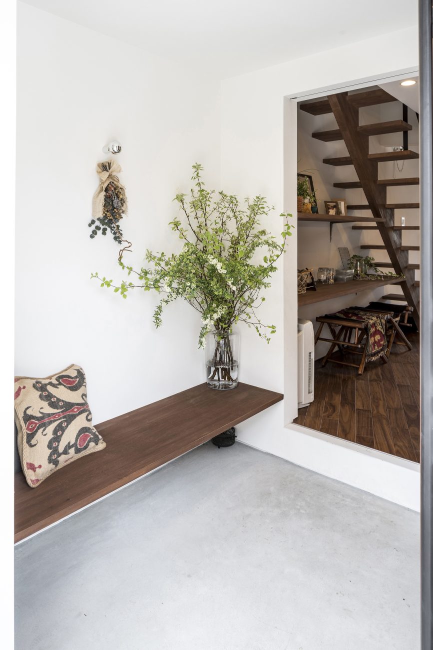 観葉植物が飾られた造作ベンチがあるモルタルの玄関・デザイン住宅 注文住宅・デザイン住宅建築実例_『CASE583 デルタ』_玄関