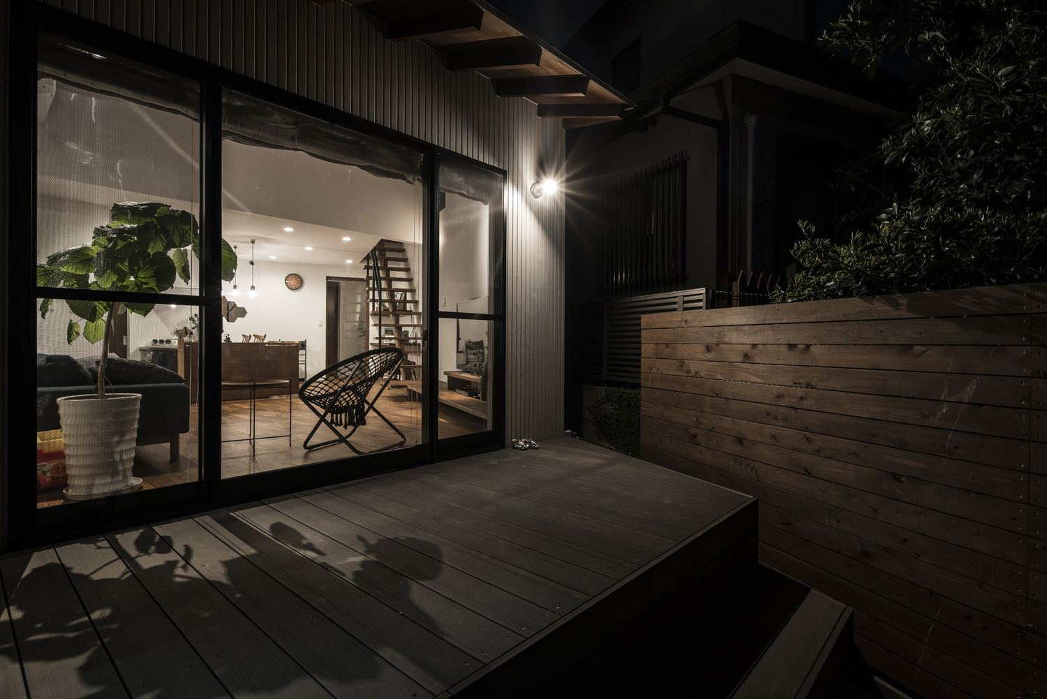 壁にスポットライトが取り付けられたLDKに面したウッドデッキのテラス・デザイン住宅 注文住宅・デザイン住宅建築実例_『CASE583 デルタ』_テラス・バルコニー