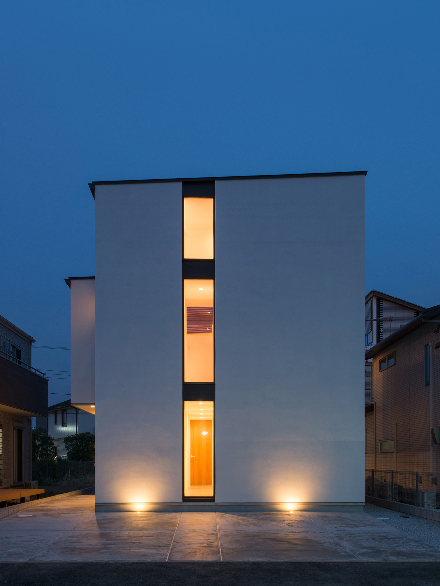 白い外壁が屋外照明に照らされる縦長のスリット窓がある・デザイン住宅 注文住宅・デザイン住宅建築実例_『CASE584 ソラノスキマ』_外観