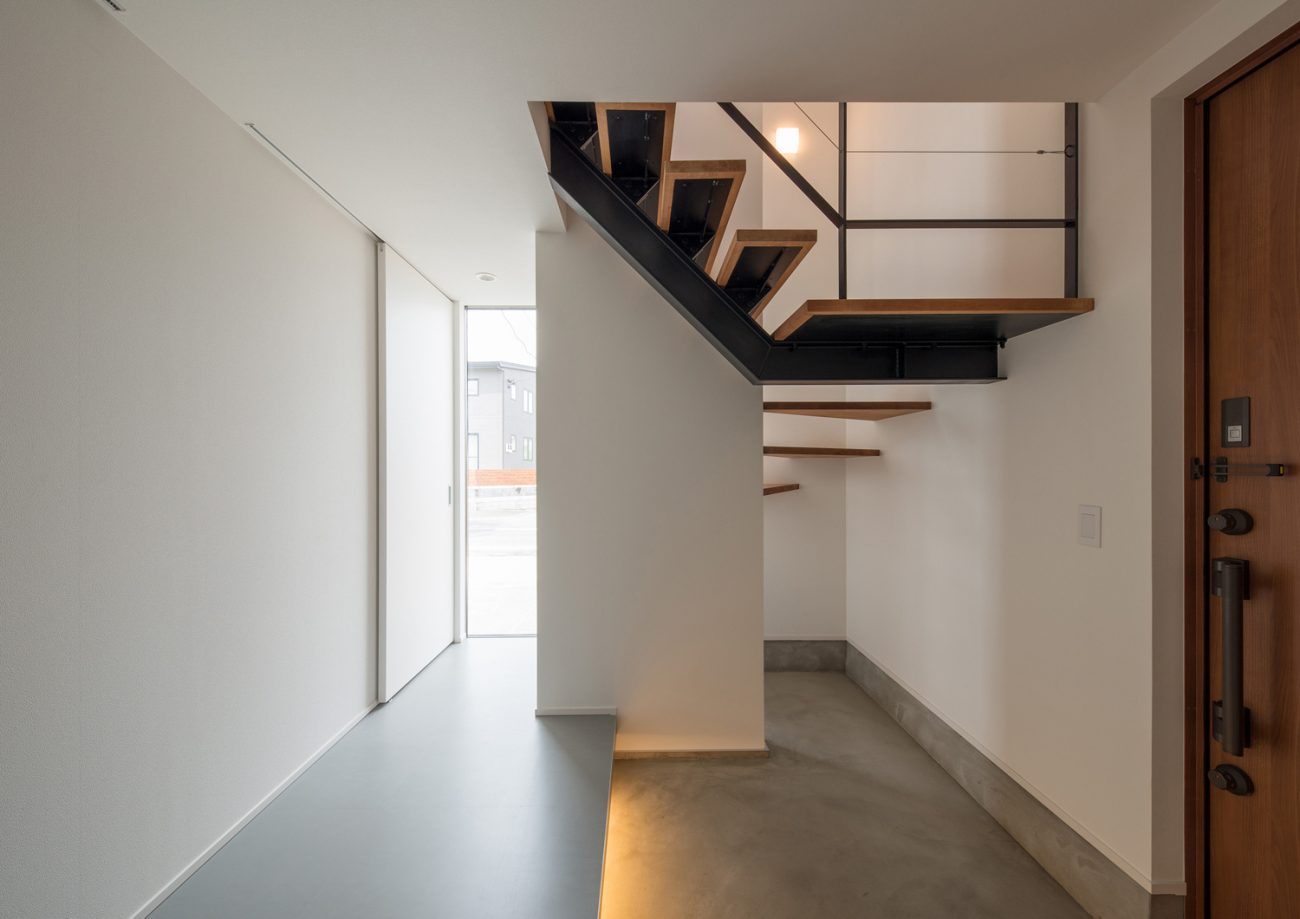 スケルトン階段が横切るモルタルの玄関・デザイン住宅 注文住宅・デザイン住宅建築実例_『CASE584 ソラノスキマ』_玄関