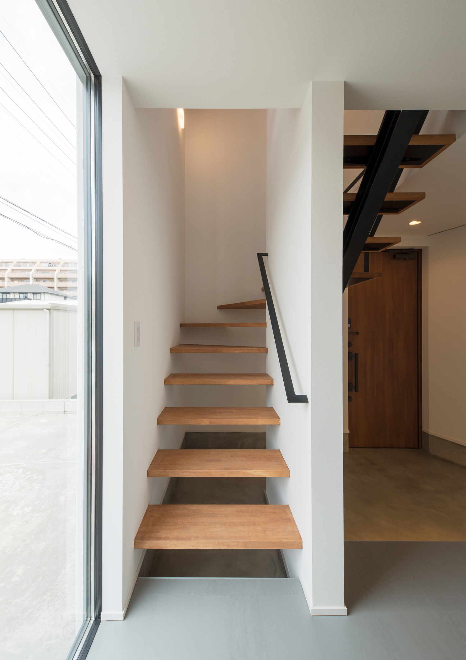 グレーの床のフロアから木目のスケルトン階段が繋がっている様子・デザイン住宅 注文住宅・デザイン住宅建築実例_『CASE584 ソラノスキマ』_階段