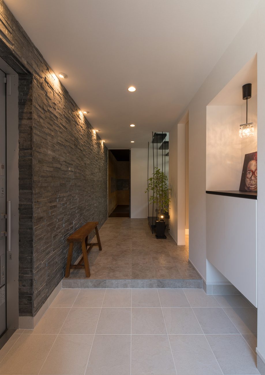 ダウンライトに照らされた石の壁がある玄関・デザイン住宅 注文住宅・デザイン住宅建築実例_『CASE585 いしのいえ』_玄関