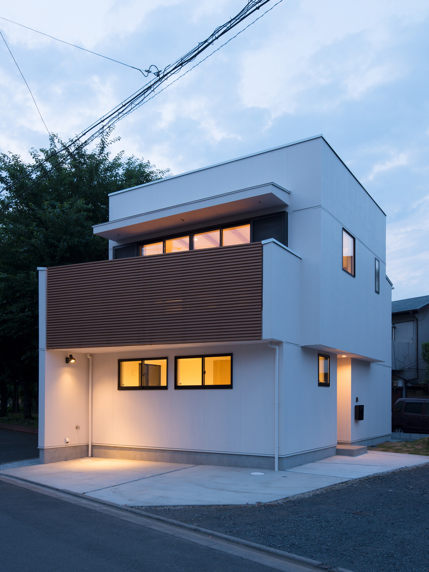 駐車スペースの壁に照明を取り付けた家を斜めから見た様子・デザイン住宅 注文住宅・デザイン住宅建築実例_『CASE586 サクラクリヒノキ』_外観