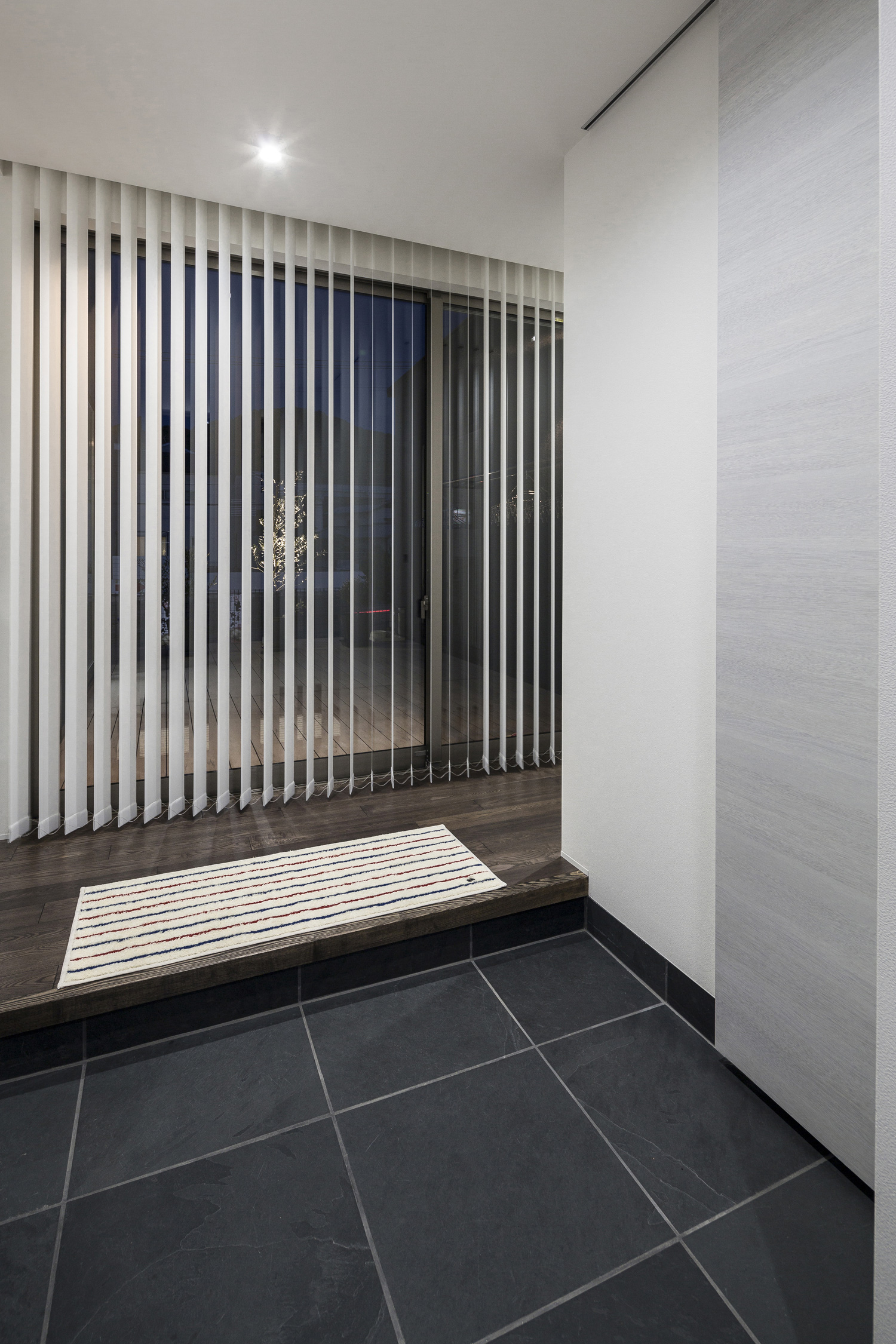 正面にブラインド付きの窓がある黒いタイルの玄関・デザイン住宅 注文住宅・デザイン住宅建築実例_『CASE587 Nero』_玄関