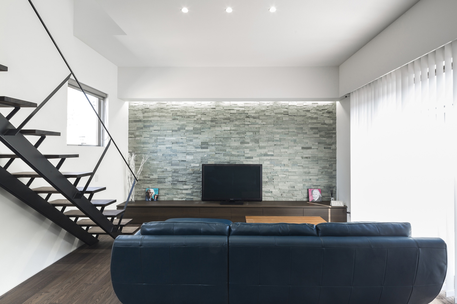 石のアクセントウォールの前にテレビが置かれたリビングイン階段のあるLDK・デザイン住宅 注文住宅・デザイン住宅建築実例_『CASE587 Nero』_LDK
