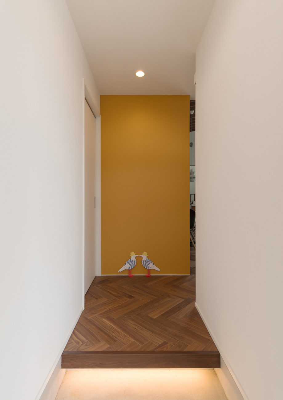 正面に黄色のクロスがあるヘリンボーン柄の床の玄関・デザイン住宅 注文住宅・デザイン住宅建築実例_『CASE588 涅の櫂』_玄関