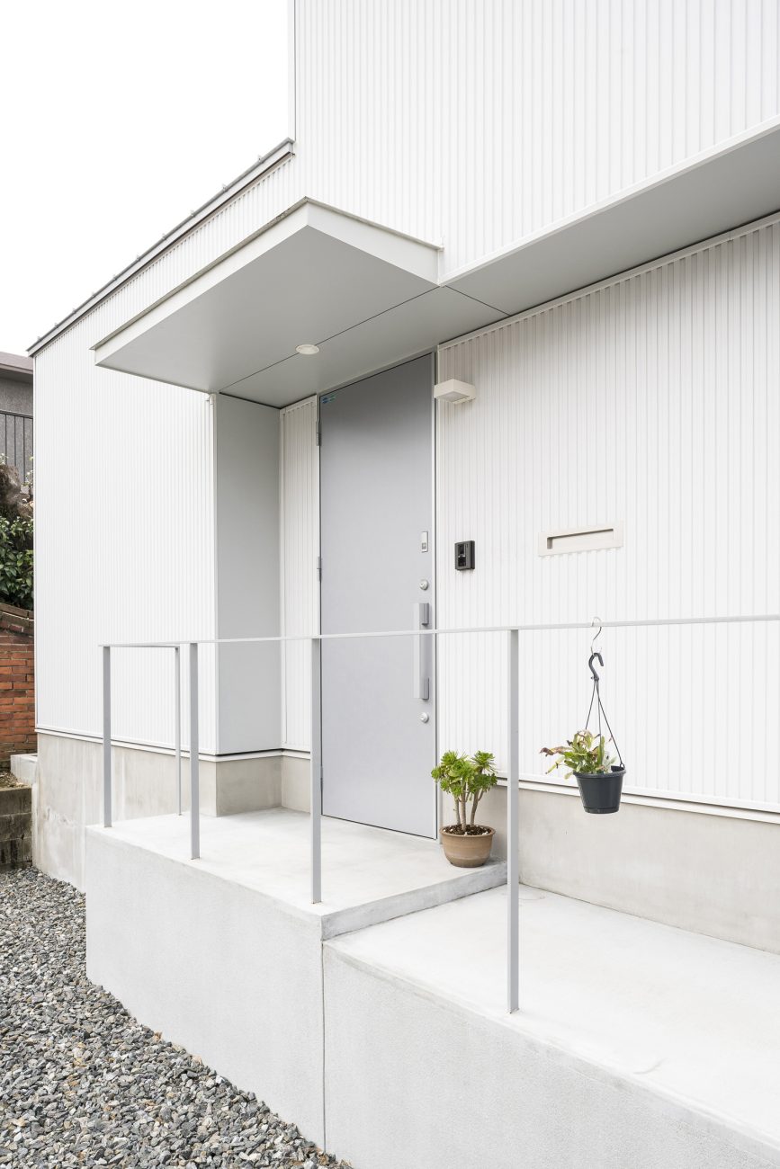 窓のない白い外壁にグレーの玄関扉が取り付けられた家・デザイン住宅 注文住宅・デザイン住宅建築実例_『CASE589 pinwheel』_外観
