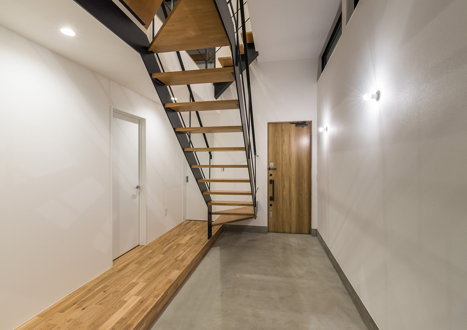 壁に照明が取り付けられたモルタルの土間玄関・デザイン住宅 注文住宅・デザイン住宅建築実例_『CASE590 つなぐ家』_玄関