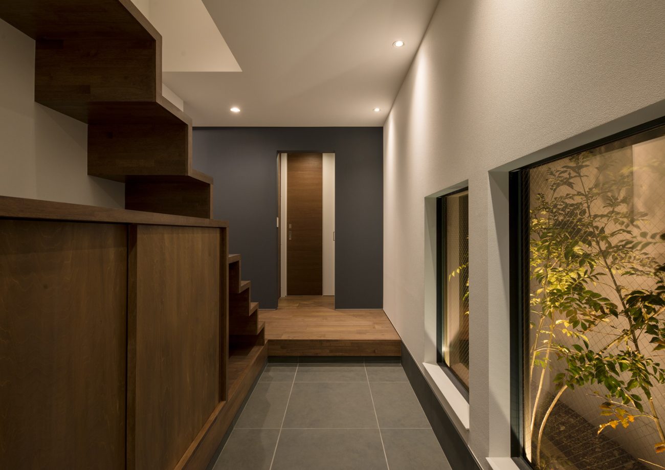 窓からライトアップされた植栽が見えるタイル貼りの玄関・デザイン住宅 注文住宅・デザイン住宅建築実例_『CASE596 【edge】』_玄関